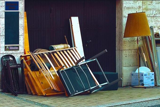 Sperrmüll aus alten Möbeln, Stühlen und einer Stehlampe zur fachgerechten Entsorgung bereitgestellt